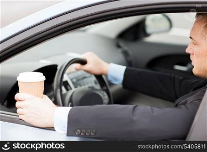 transportation and vehicle concept - man drinking coffee while driving the car