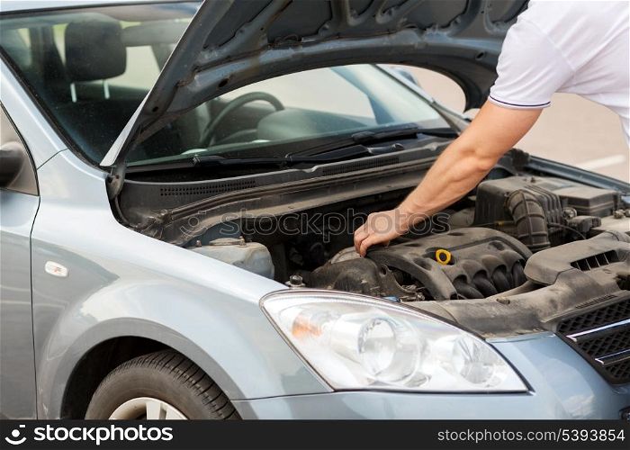 transportation and vehicle concept - man opening car bonnet and looking under hood
