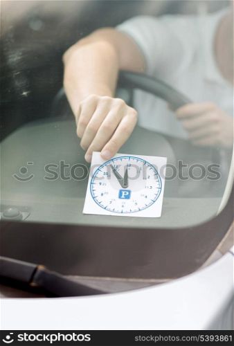 transportation and vehicle concept - man placing parking clock on car dashboard under windscreen