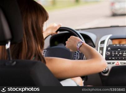 transportation and vehicle concept - woman driving a car and looking at watch