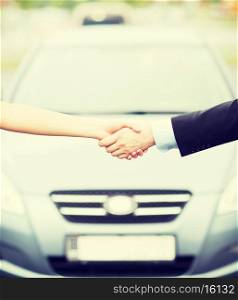 transportation, business, shopping and ownership concept - customer and salesman shaking hands outside