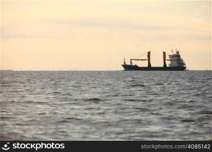 Transportation, cargo conteiner ship sailing in still water heading for the port against sunset sky
