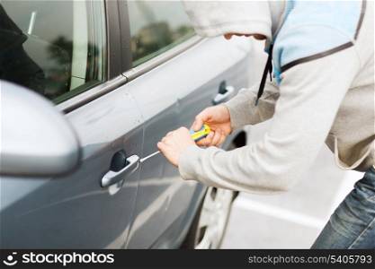 transportation, crime and ownership concept - thief breaking the car lock