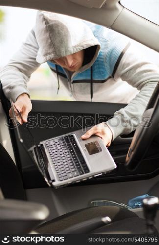 transportation, crime and ownership concept - thief stealing laptop from the car