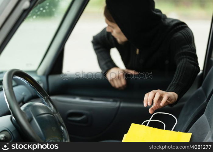 Transportation, crime and ownership concept - thief stealing shopping bag from the car