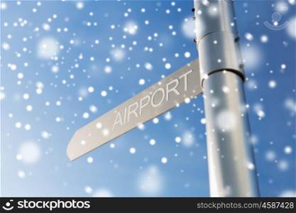 transportation, direction, location, travel and road sign concept - close up of airport signpost over blue sky background with snow