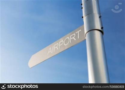 transportation, direction, location, travel and road sign concept - close up of airport signpost over blue sky background