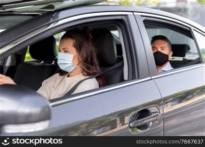 transportation, health and people concept - female driver driving car with male passenger wearing face protective medical mask for protection from virus disease. female driver in mask driving car with passenger