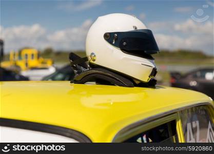 transportation, high speeds, racing and road concept - close up of car on autodrome or parking with helmet on roof top