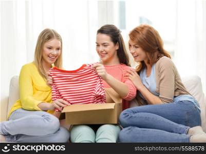 transportation, post and friendship concept - three smiling teenage girls opening cardboard box at home