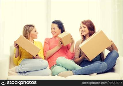 transportation, post and friendship concept - three smiling teenage girls with cardboard boxes at home