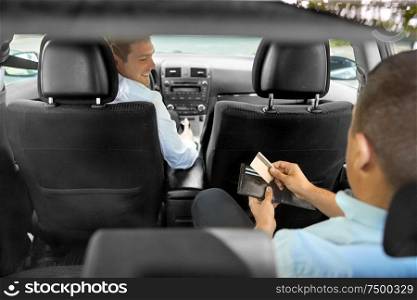transportation, taxi and payment concept - male car driver looking at passenger with credit card in wallet. male car driver looking at passenger with wallet