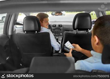 transportation, taxi and payment concept - male car driver looking at passenger with money in wallet. male car driver looking at passenger with money