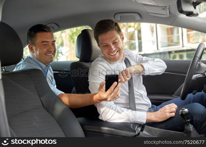 transportation, taxi and technology concept - middle aged male passenger on back seat showing his smartphone to car driver. male passenger showing smartphone to car driver