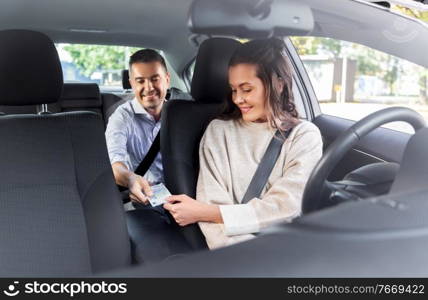 transportation, vehicle and payment concept - female car driver taking money from male passenger. female car driver taking money from passenger