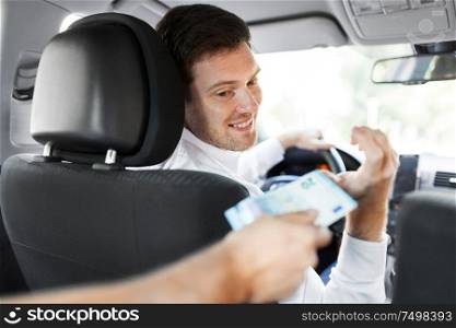 transportation, vehicle and payment concept - male car driver taking money from passenger. male car driver taking money from passenger