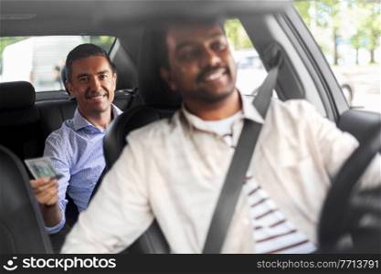 transportation, vehicle and payment concept - smiling passenger giving money to indian male taxi car driver. smiling passenger giving money to taxi car driver