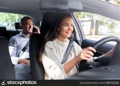transportation, vehicle and people concept - happy smiling female driver driving car with male passenger calling on phone. female driver driving car with male passenger