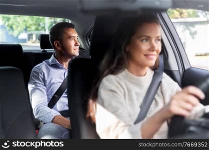 transportation, vehicle and people concept - happy smiling female driver driving car with male passenger. female driver driving car with male passenger
