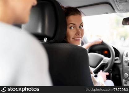 transportation, vehicle and people concept - happy smiling female driver driving car with passenger. female driver driving car with passenger