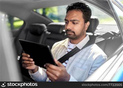 transportation, vehicle and people concept - indian male passenger with tablet pc computer in taxi car. indian male passenger with tablet pc in taxi car