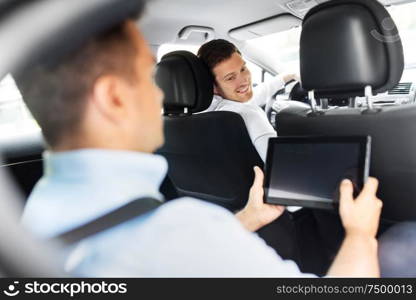 transportation, vehicle and people concept - male car driver looking at passenger with tablet pc computer sitting on back seat. male car driver and passenger with tablet pc
