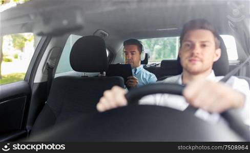 transportation, vehicle and people concept - middle aged male passenger with tablet pc computer and headphones on back seat and car driver. man with tablet pc and headphones riding in car