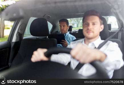 transportation, vehicle and people concept - middle aged male passenger with tablet pc computer and wireless earphones on back seat and car driver. man with tablet pc and earphones riding in car