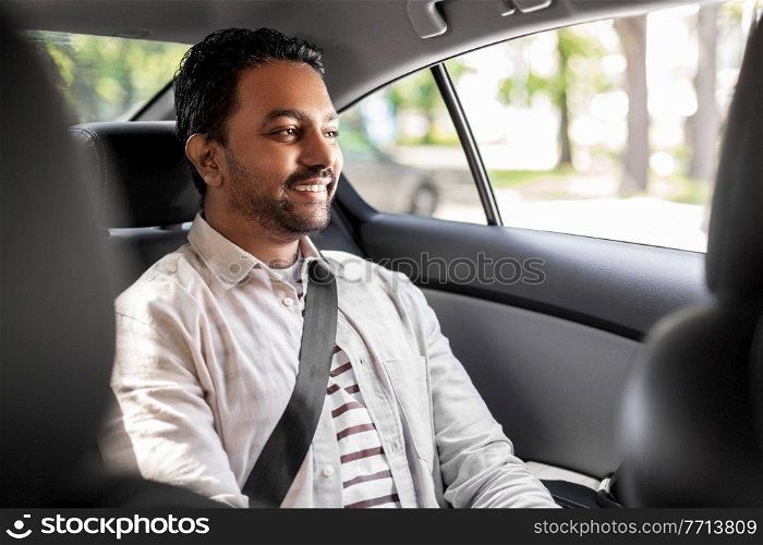 transportation, vehicle and people concept - smiling indian male passenger in taxi car. smiling indian male passenger in taxi car
