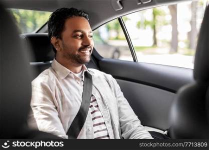 transportation, vehicle and people concept - smiling indian male passenger in taxi car. smiling indian male passenger in taxi car
