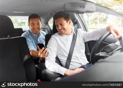 transportation, vehicle and technology concept - middle aged male passenger on back seat showing his smartphone to car driver. male passenger showing smartphone to car driver