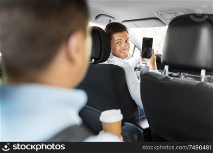 transportation, vehicle and technology concept - smiling car driver showing smartphone to male passenger. car driver showing smartphone to male passenger