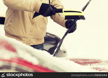 transportation, winter and vehicle concept - closeup of man cleaning snow from car windshield with brush