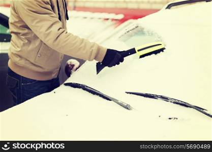 transportation, winter and vehicle concept - closeup of man cleaning snow from car windshield with brush