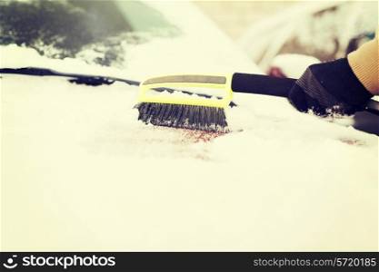 transportation, winter and vehicle concept - closeup of man cleaning snow from car windshield with brush