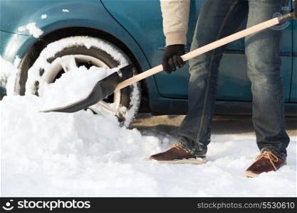 transportation, winter and vehicle concept - closeup of man digging up stuck in snow car