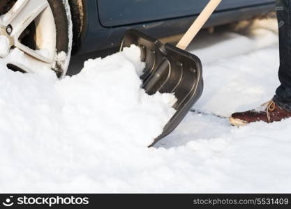 transportation, winter and vehicle concept - closeup of man digging up stuck in snow car