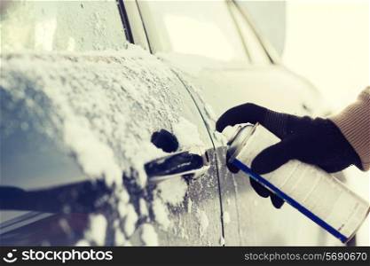 transportation, winter and vehicle concept - closeup of man hand with lock door de-icer
