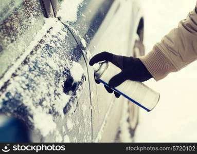 transportation, winter and vehicle concept - closeup of man hand with lock door de-icer