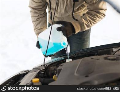 transportation, winter and vehicle concept - closeup of man pouring antifreeze into windscreen water tank