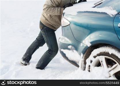 transportation, winter and vehicle concept - closeup of man pushing car stuck in snow