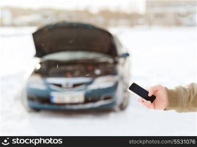 transportation, winter and vehicle concept - closeup of man with broken car and smartphone