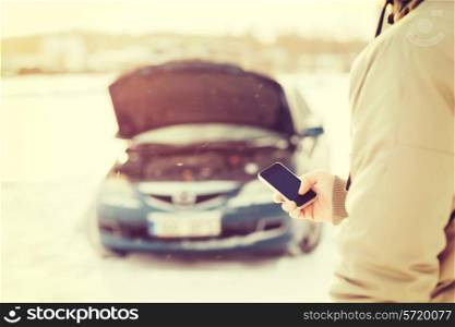 transportation, winter and vehicle concept - closeup of man with broken car and smartphone