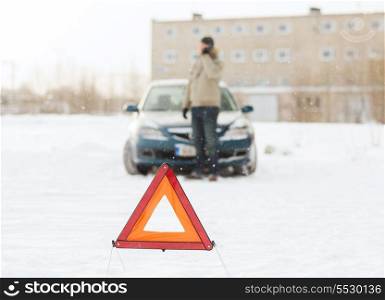 transportation, winter and vehicle concept - closeup of man with broken car, warning triangle and smartphone