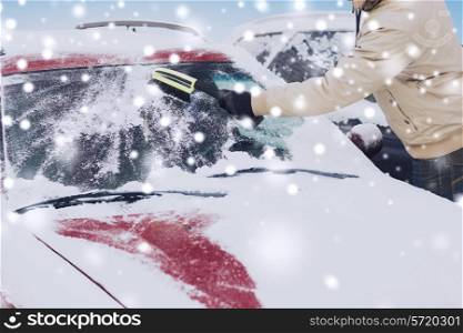 transportation, winter, people and vehicle concept - closeup of man cleaning snow from car windshield with brush