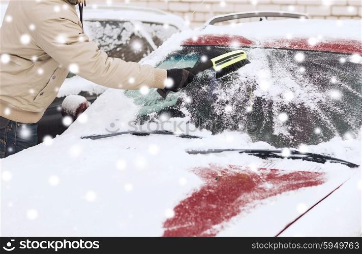 transportation, winter, people and vehicle concept - closeup of man cleaning snow from car windshield with brush