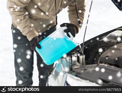 transportation, winter, people and vehicle concept - closeup of man pouring antifreeze into car