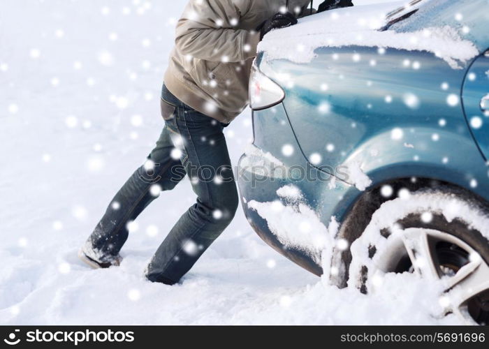 transportation, winter, people and vehicle concept - closeup of man pushing car stuck in snow