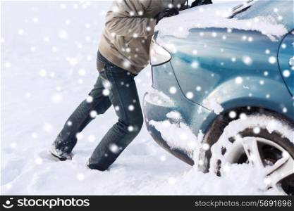transportation, winter, people and vehicle concept - closeup of man pushing car stuck in snow