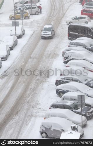 Transportation, winter season and seasonal specific. Parked cars covered in snow after blizzard and urban road street, top view. Road and parked cars covered in snow after blizzard